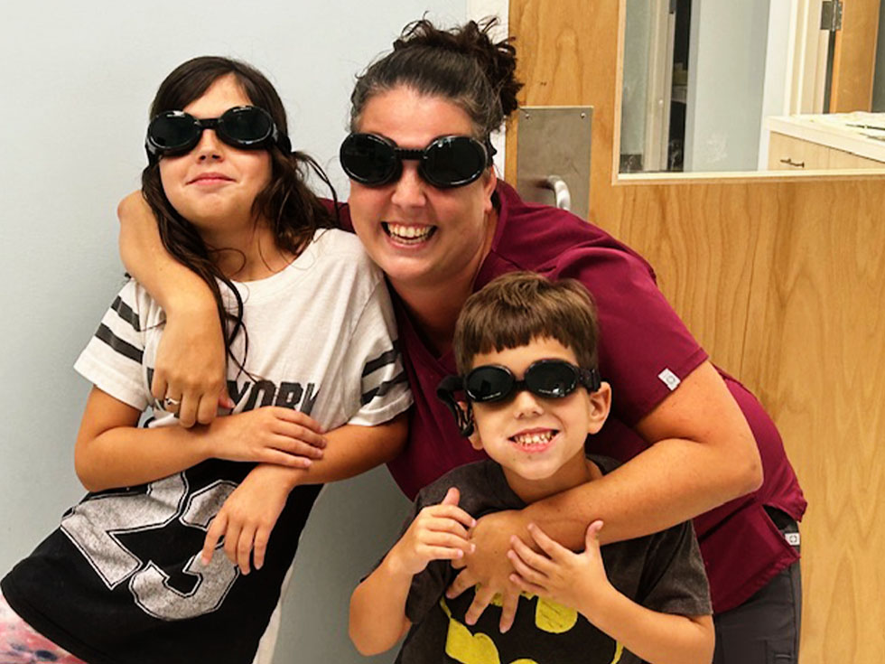 woman hugging two children with x-ray protective glasses